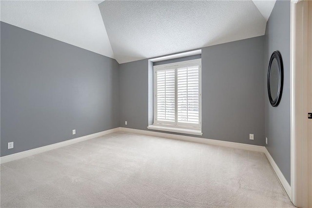 empty room with baseboards, lofted ceiling, carpet, and a textured ceiling