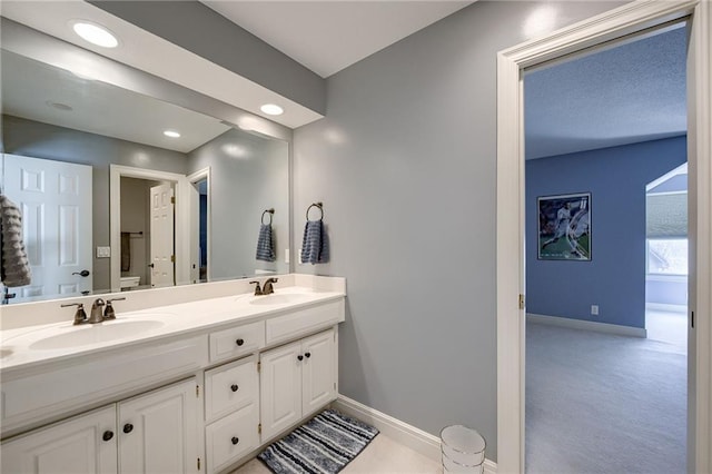 bathroom featuring double vanity, recessed lighting, baseboards, and a sink