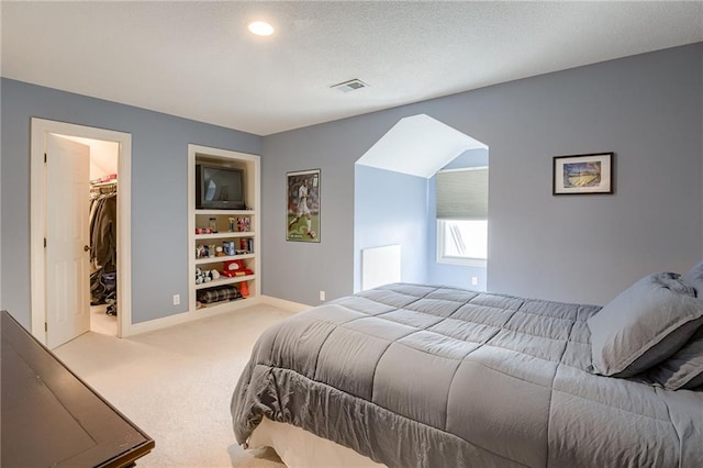 bedroom with visible vents, baseboards, carpet floors, a spacious closet, and a textured ceiling