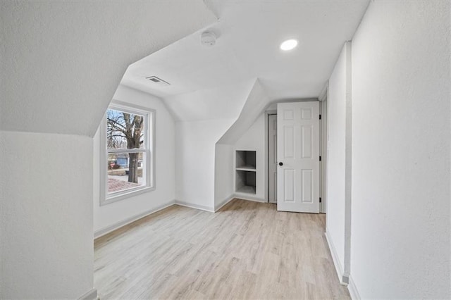 additional living space featuring visible vents, lofted ceiling, a textured ceiling, light wood finished floors, and baseboards