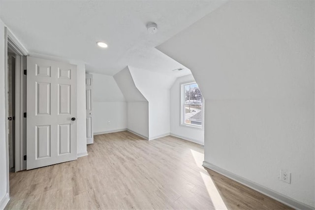 additional living space with lofted ceiling, light wood-style flooring, and baseboards