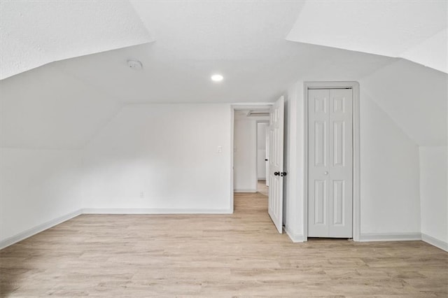 additional living space featuring lofted ceiling, light wood-style flooring, and baseboards