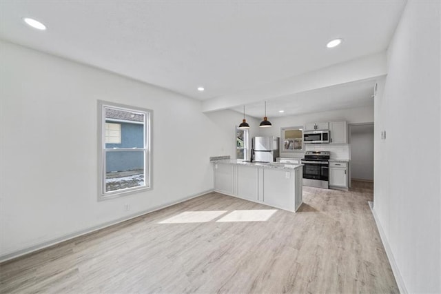 kitchen with light countertops, light wood-type flooring, recessed lighting, appliances with stainless steel finishes, and a peninsula