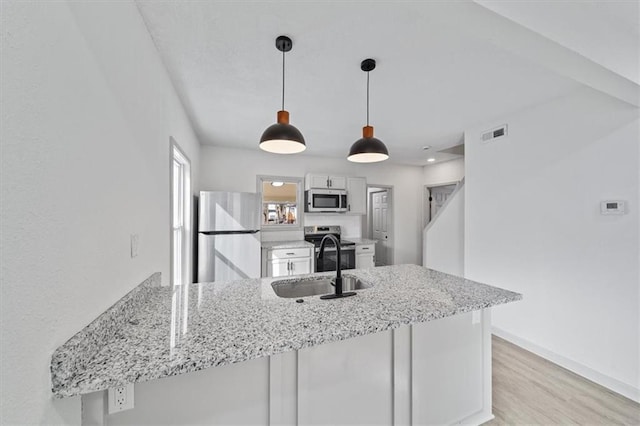 kitchen with visible vents, light wood-style flooring, appliances with stainless steel finishes, a peninsula, and a sink