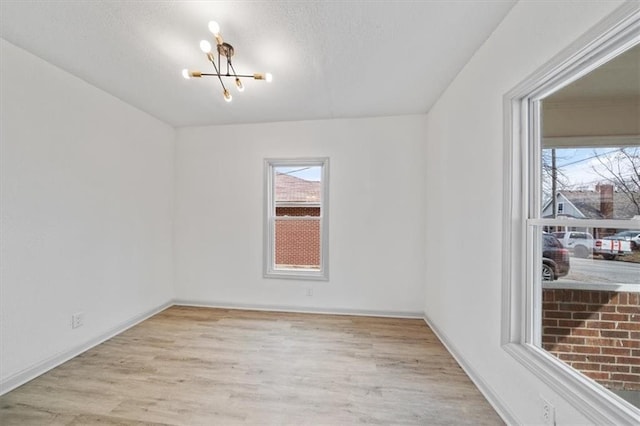 unfurnished room with a wealth of natural light, a notable chandelier, wood finished floors, and a textured ceiling