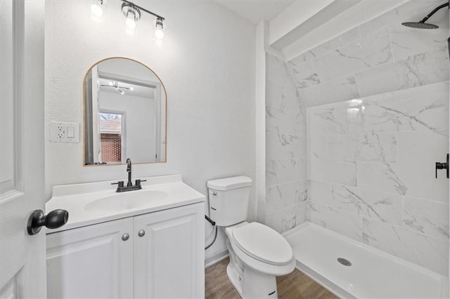 bathroom with a shower stall, baseboards, toilet, wood finished floors, and vanity