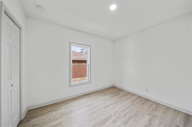 unfurnished bedroom with a closet, baseboards, and light wood-style flooring