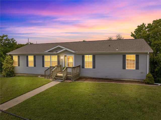 ranch-style house with a yard and a shingled roof