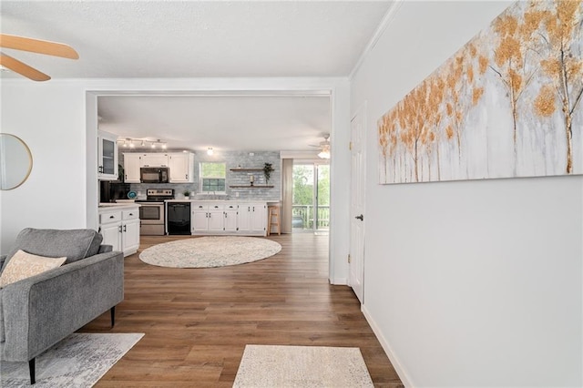 1310 Lawrence Ave, Kansas City, KS 66103 - living area with dark wood finished floors, crown molding, a ceiling fan, and baseboards