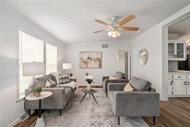 1310 Lawrence Ave, Kansas City, KS 66103 - living room featuring visible vents, a textured ceiling, wood finished floors, and ornamental molding