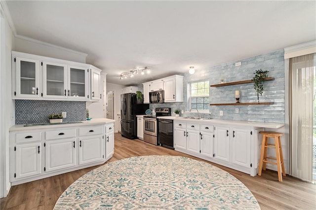 1310 Lawrence Ave, Kansas City, KS 66103 - kitchen with light wood-type flooring, black appliances, light countertops, and a sink