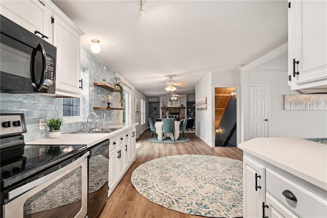 1310 Lawrence Ave, Kansas City, KS 66103 - kitchen with a fireplace, ceiling fan, a sink, black appliances, and tasteful backsplash