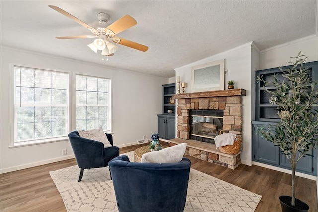 1310 Lawrence Ave, Kansas City, KS 66103 - living room with ornamental molding, a textured ceiling, wood finished floors, a stone fireplace, and baseboards