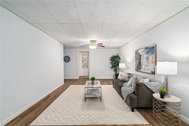 1310 Lawrence Ave, Kansas City, KS 66103 - living room featuring a drop ceiling, baseboards, a ceiling fan, and dark wood-style flooring