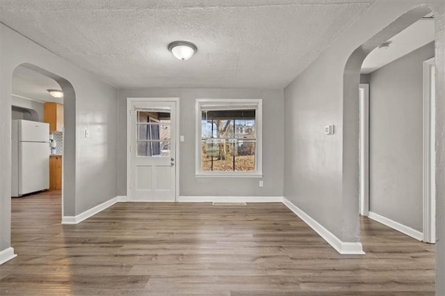 entrance foyer featuring arched walkways, wood finished floors, and baseboards