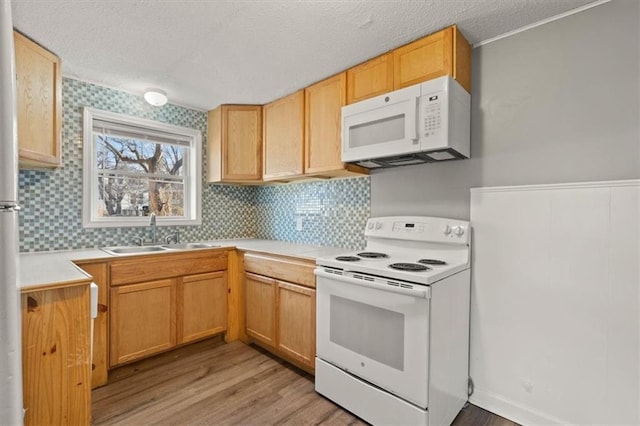 kitchen with white appliances, light countertops, a textured ceiling, light wood-style floors, and a sink