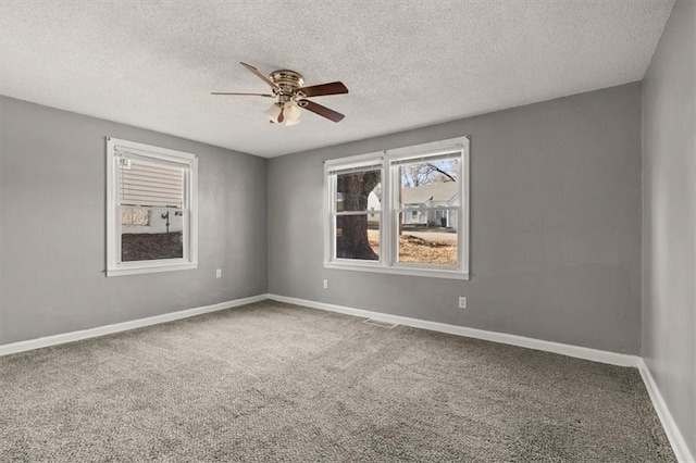 empty room featuring visible vents, a ceiling fan, carpet flooring, a textured ceiling, and baseboards