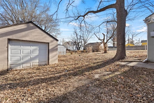 view of yard featuring a garage, driveway, an outdoor structure, and fence