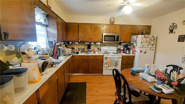 kitchen featuring white appliances, brown cabinetry, and light countertops