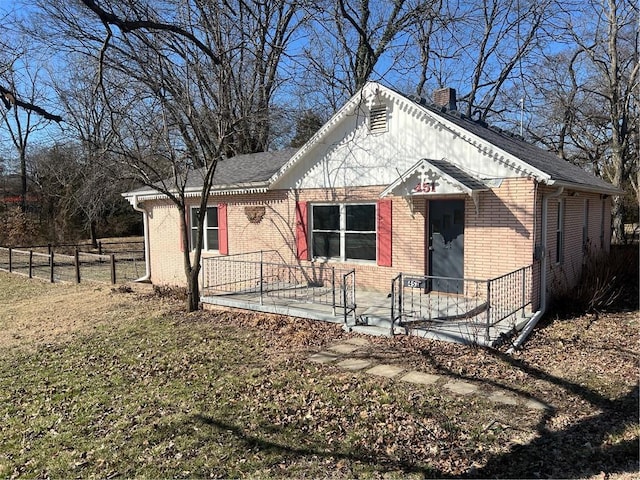 view of front of property with brick siding, a chimney, and fence