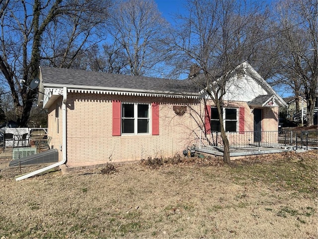 view of front of house with brick siding, a front yard, a patio, and roof with shingles