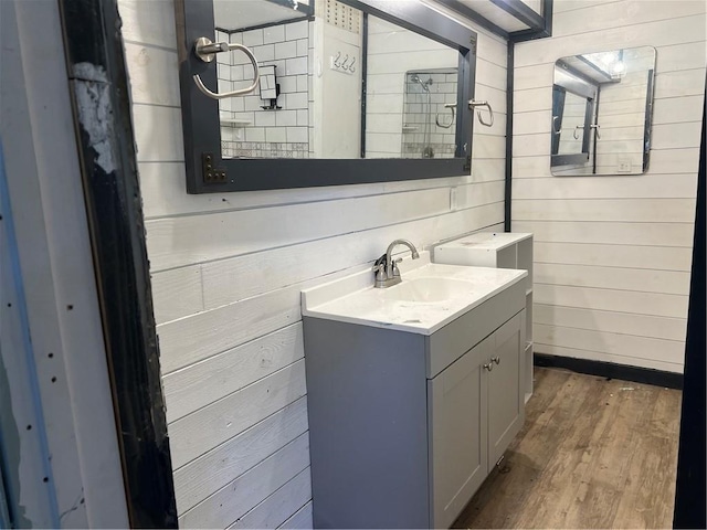 bathroom with vanity, wood finished floors, and wood walls