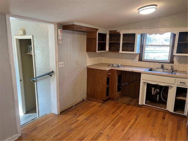 kitchen with a sink, vaulted ceiling, decorative backsplash, light wood-style floors, and open shelves