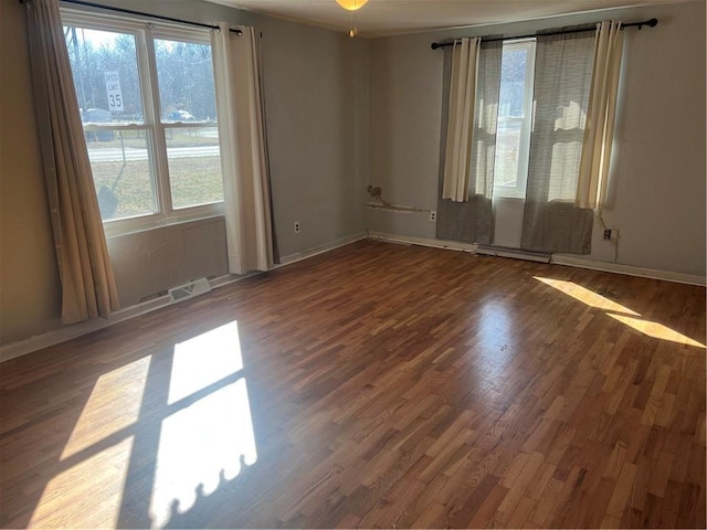 empty room with visible vents, baseboards, and wood finished floors