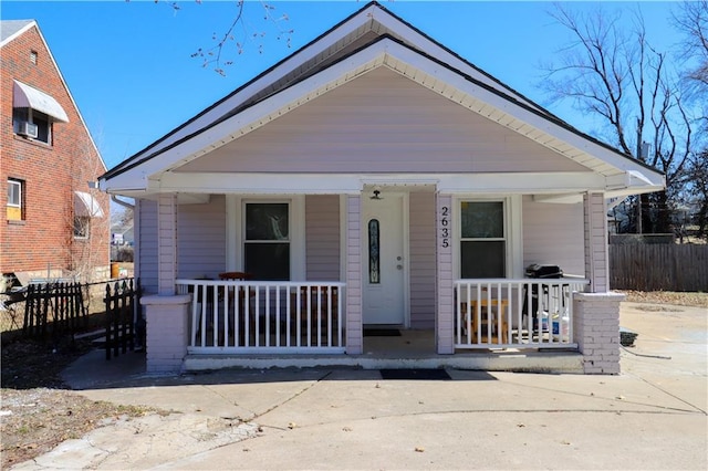 bungalow featuring covered porch and fence