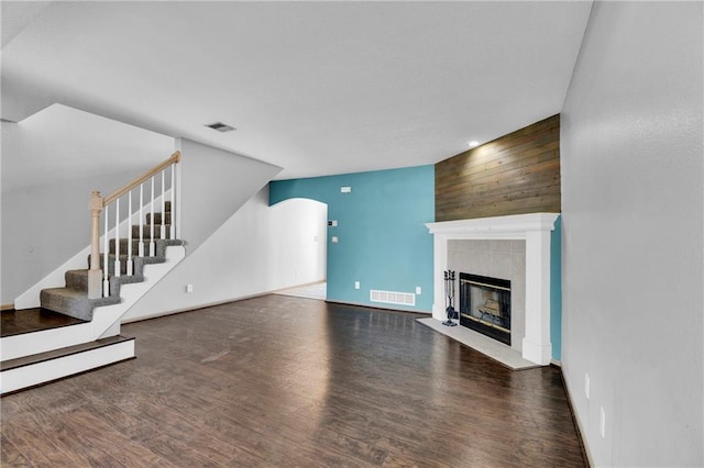 unfurnished living room with visible vents, a fireplace, stairway, and wood finished floors