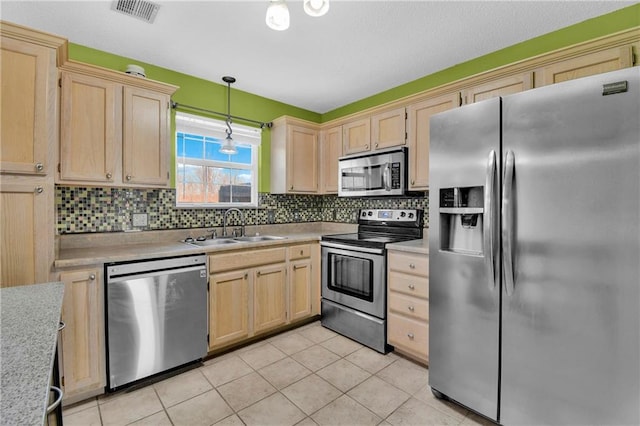 kitchen with light brown cabinets, visible vents, a sink, stainless steel appliances, and light countertops