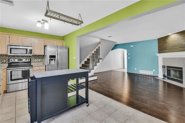 kitchen featuring visible vents, open floor plan, stainless steel appliances, a fireplace, and light countertops