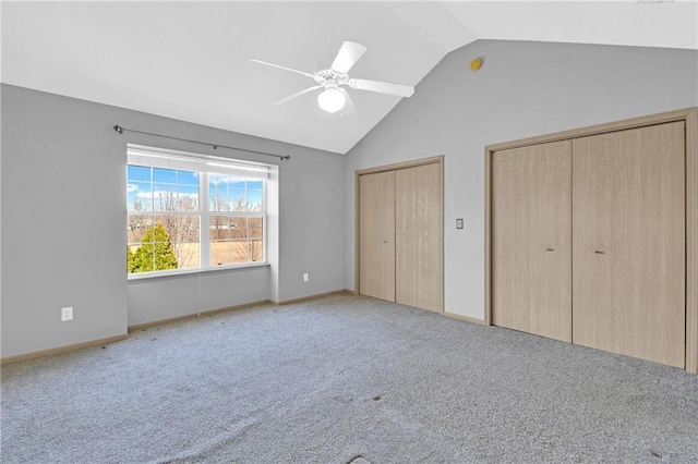 unfurnished bedroom with two closets, lofted ceiling, a ceiling fan, carpet floors, and baseboards