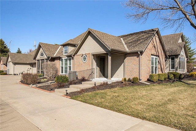 english style home with driveway, brick siding, a front lawn, and a shingled roof