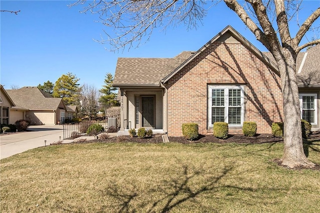 view of front of home with brick siding, a front lawn, and roof with shingles