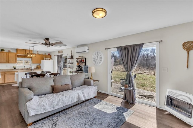 living area featuring dark wood-style flooring, a ceiling fan, baseboards, a wall mounted AC, and heating unit