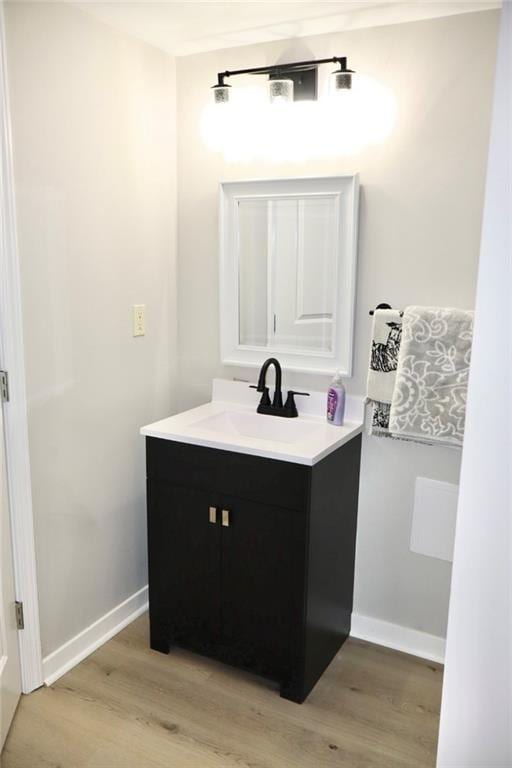 bathroom with vanity, wood finished floors, and baseboards