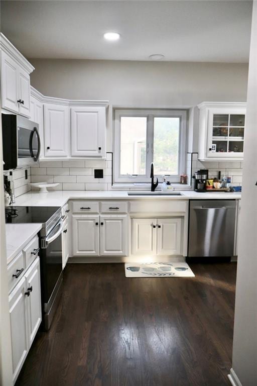 kitchen featuring dark wood-style flooring, a sink, light countertops, white cabinets, and appliances with stainless steel finishes