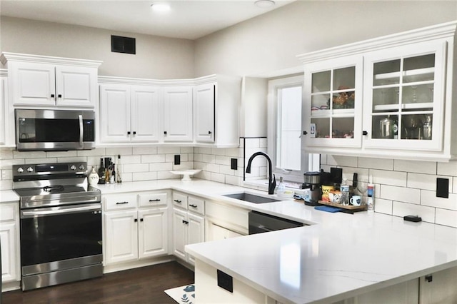 kitchen with visible vents, a peninsula, a sink, white cabinets, and appliances with stainless steel finishes