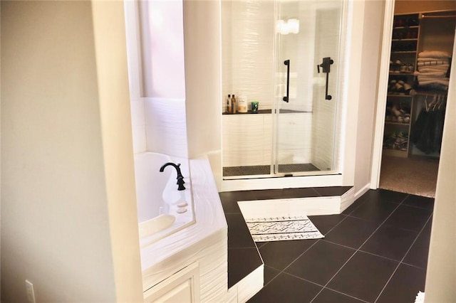 bathroom with tile patterned floors, a shower stall, a spacious closet, and a garden tub