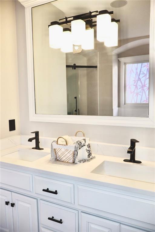 bathroom featuring double vanity, a stall shower, and a sink