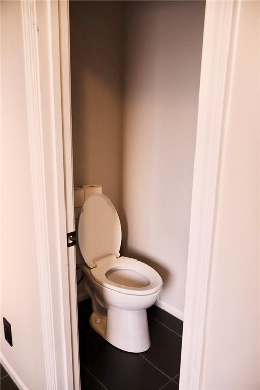 bathroom with tile patterned floors, toilet, and baseboards