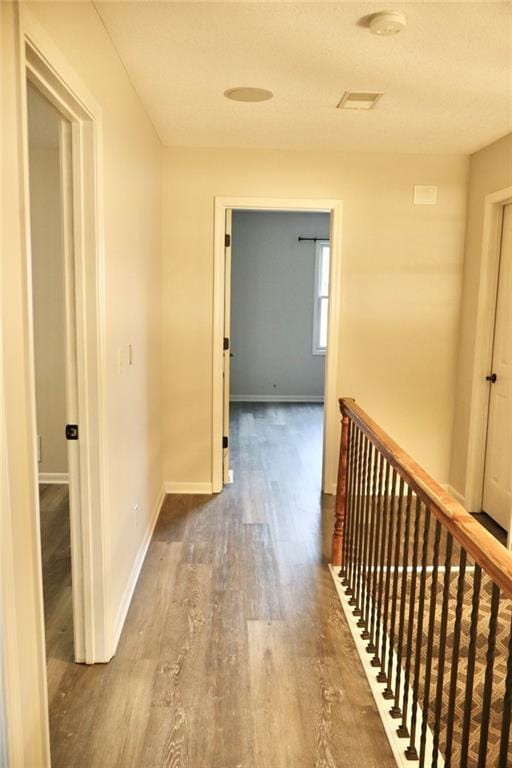 hallway featuring an upstairs landing, baseboards, and wood finished floors