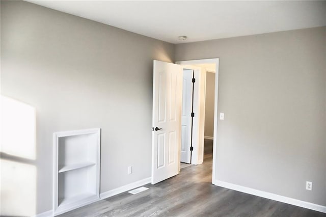 unfurnished bedroom featuring dark wood-type flooring and baseboards