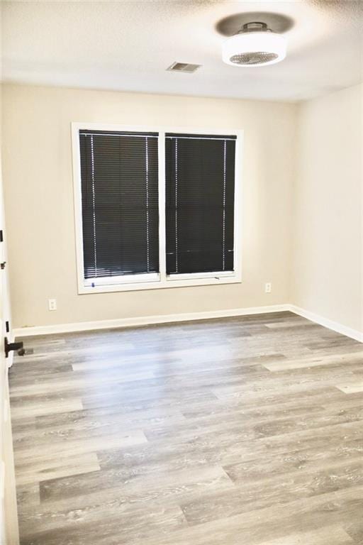 empty room with visible vents, baseboards, and wood finished floors