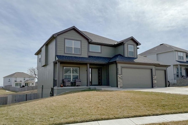 view of front of home with concrete driveway, stone siding, roof with shingles, an attached garage, and a front yard