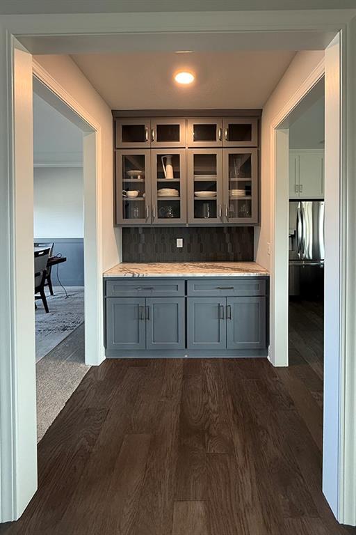 bar with backsplash and dark wood-type flooring