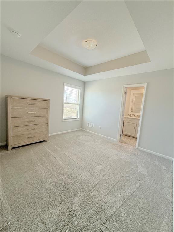 unfurnished bedroom featuring carpet floors, a tray ceiling, and visible vents