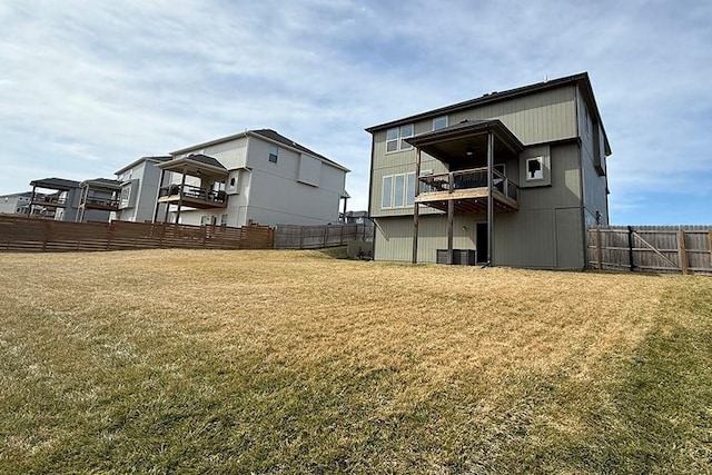 rear view of house with a lawn, fence, and a balcony