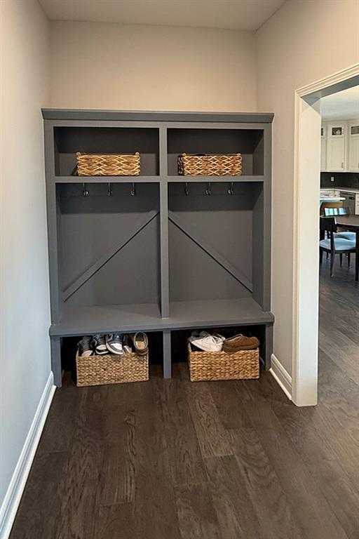 mudroom with dark wood finished floors and baseboards